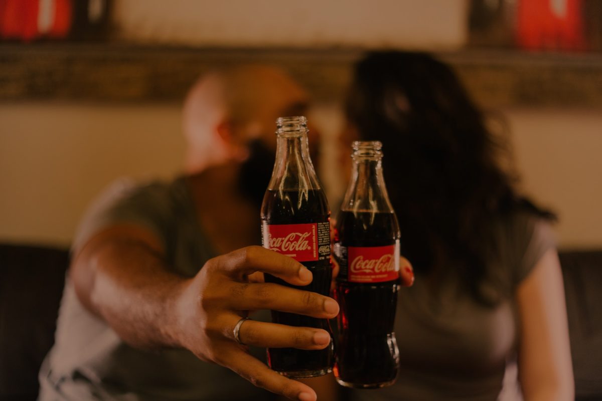 dos personas detrás de dos botellas de vidrio de Coca cola